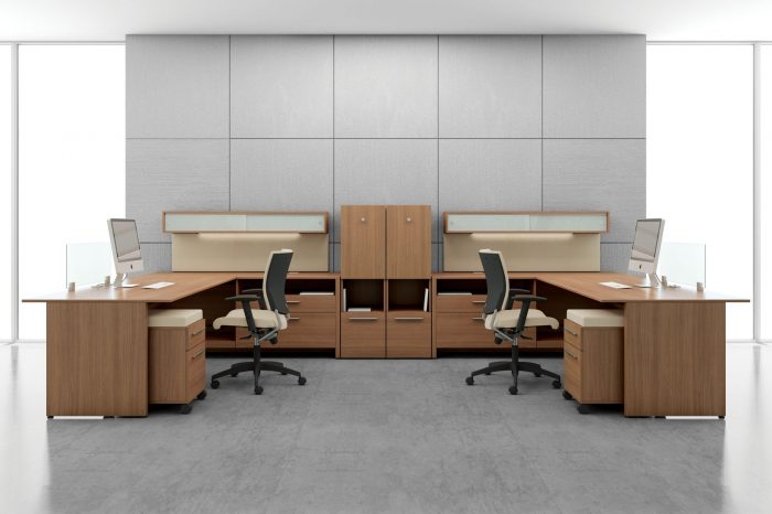 Studio shot of two L-shaped desks, with full sized windows on each side. A Graphic posture back chair is placed at each workstation.