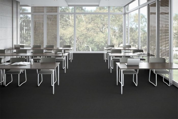 Accelerate flooring in a classroom setting. Tall windows allow light in from the outside.