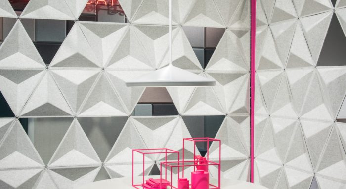 Studio photography into a corner, formed by two sets of Aircone acoustics. A round white table holds a pink wire display. The foam material forms geometric shapes.