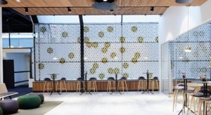 Studio shot of Airflake acoustics set up in a large lounge area. Tall cocktail tables and barstools are placed along the back wall. Airflake acoustics are placed along the wall, backlit in white.