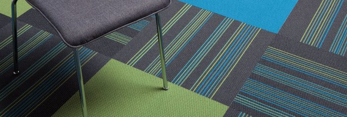 Studio shot of colorful Pop carpet squares, with a metal frame classroom chair set on top.