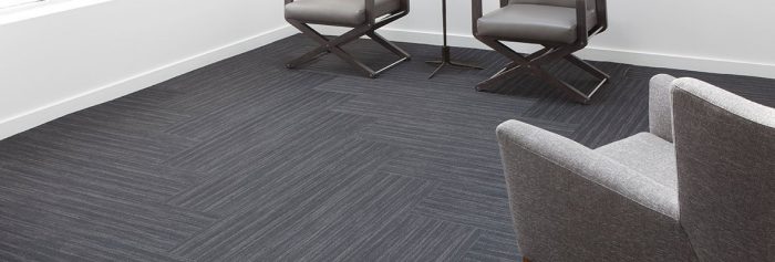 Studio photography of a waiting area, using Timber carpeting. It is arranged in a herringbone pattern.