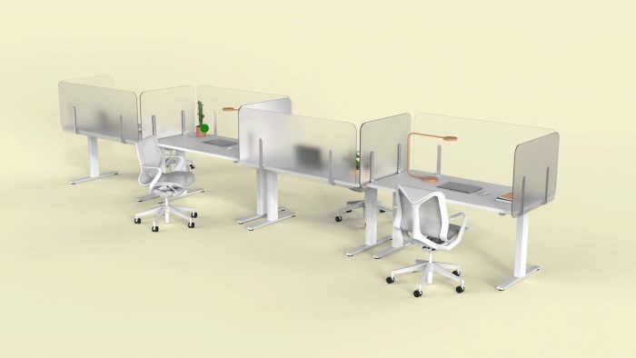 Four single tables placed together, with Shelter partition screens lining each. Each of the four work areas has a desk lamp, laptop, and a few folders to look at.