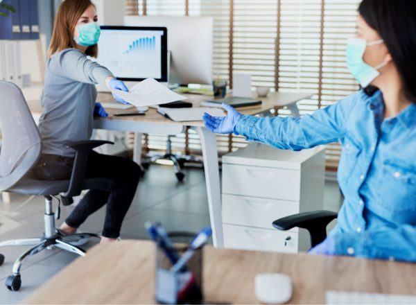 two women socially distancing at the office with masks